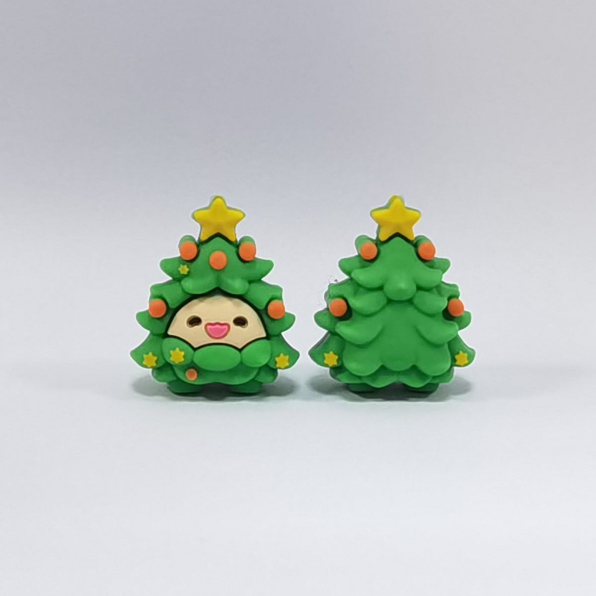 Two green Christmas tree silicone focal beads with yellow star toppers and orange ornaments, one with cute face