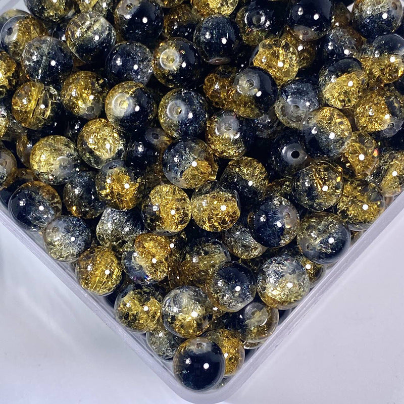 Assorted black and gold crackle glass beads in a container