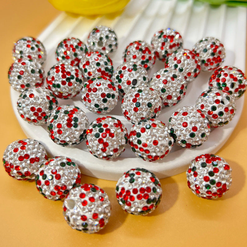 Silver Christmas beads with red and green rhinestones on a white plate.
