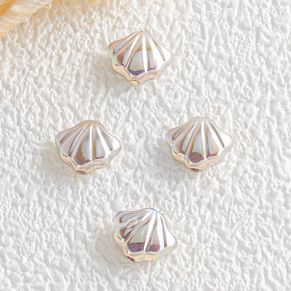Four small pearly shell-shaped beads arranged on a textured white surface