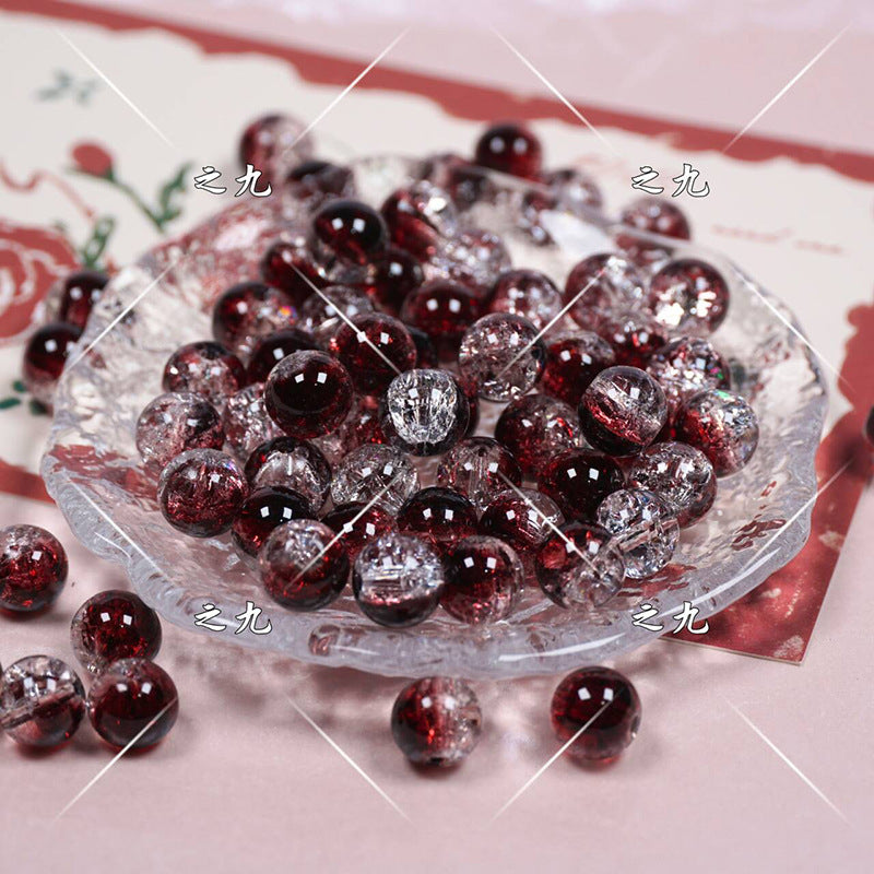 Red and clear crackle glass beads on a decorative plate with a floral pattern