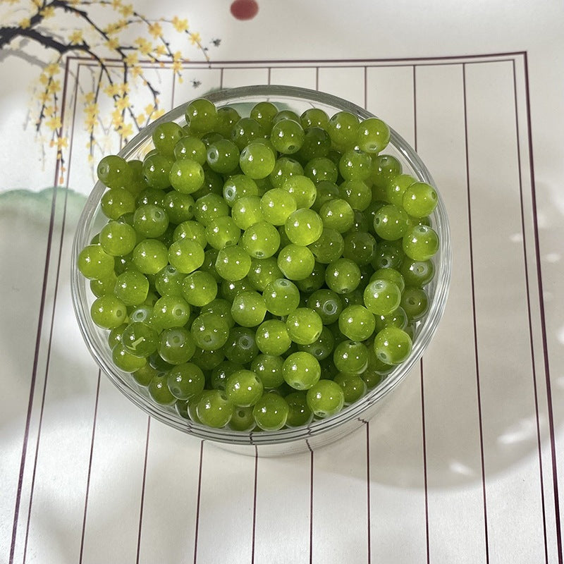 Bright green round beads in a clear container on white surface with brown lines