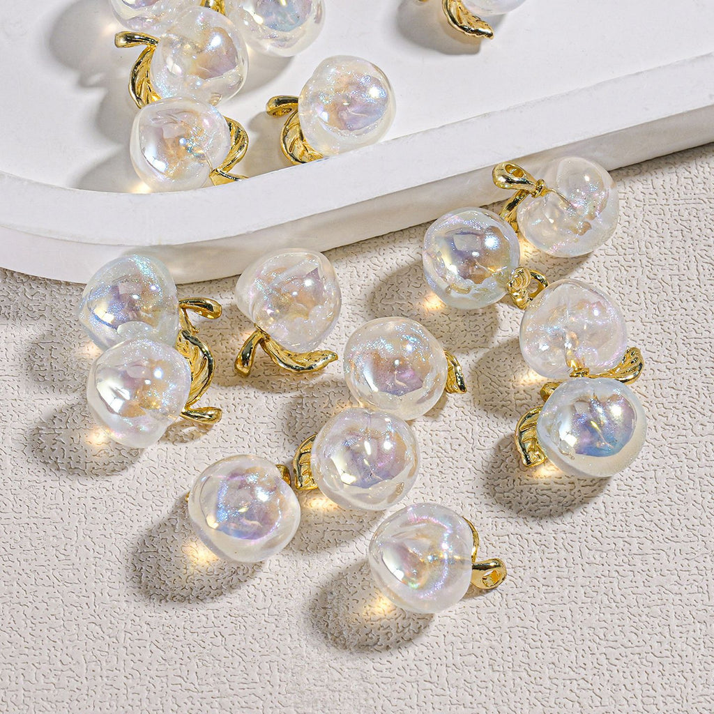 Gold-plated ring settings with large round iridescent mini peach beads on a textured surface