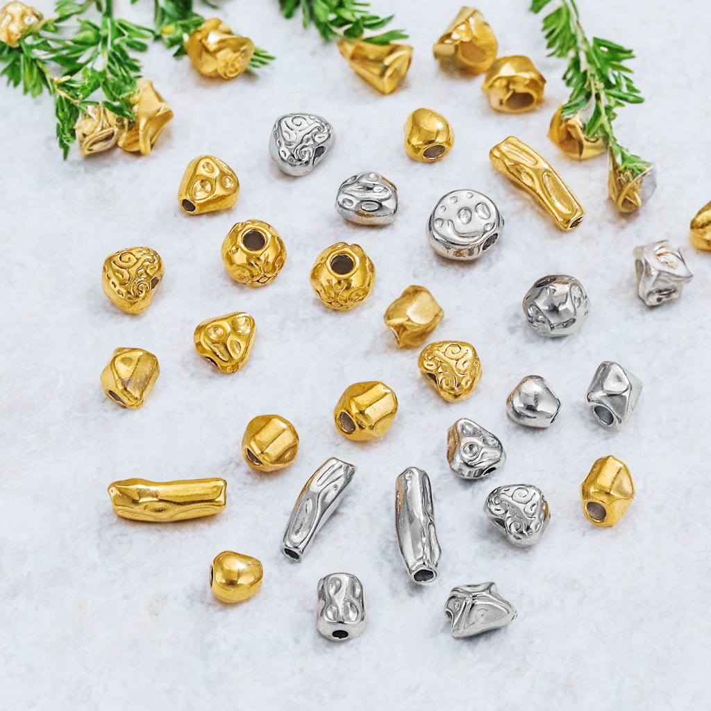 Baroque irregular stainless steel spacer beads in gold and steel colors with green leaves on light background