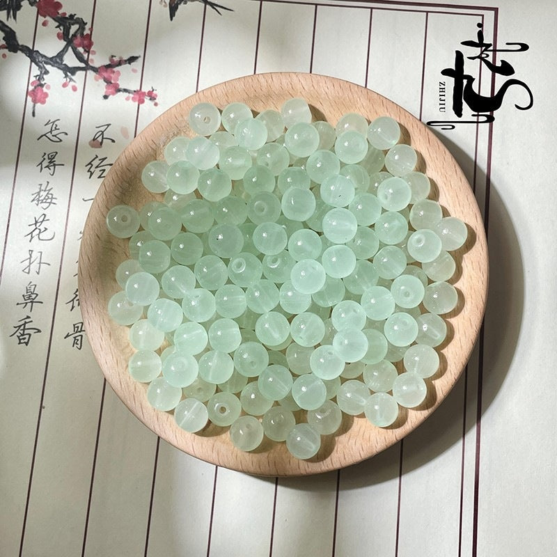 Pale green translucent round beads on a wooden plate with calligraphy background