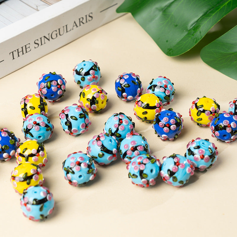 Round perforated glass pendant beads in blue, yellow, and light blue with floral dot patterns