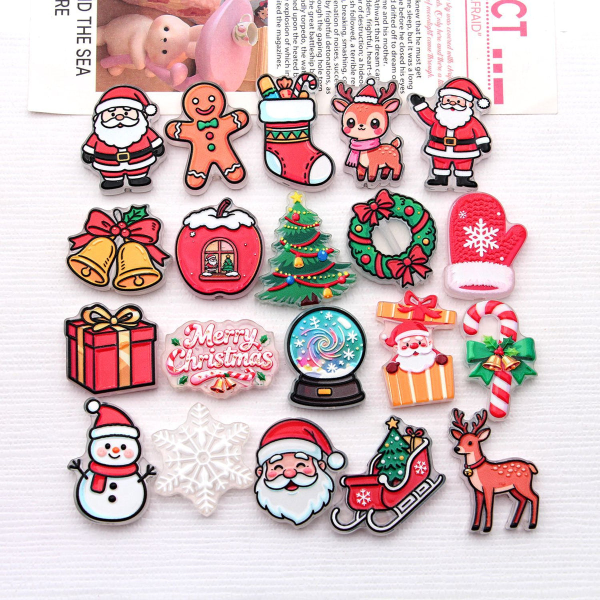 Flat lay of colorful Christmas acrylic pendant charms including Santa, reindeer, tree, snowman on white