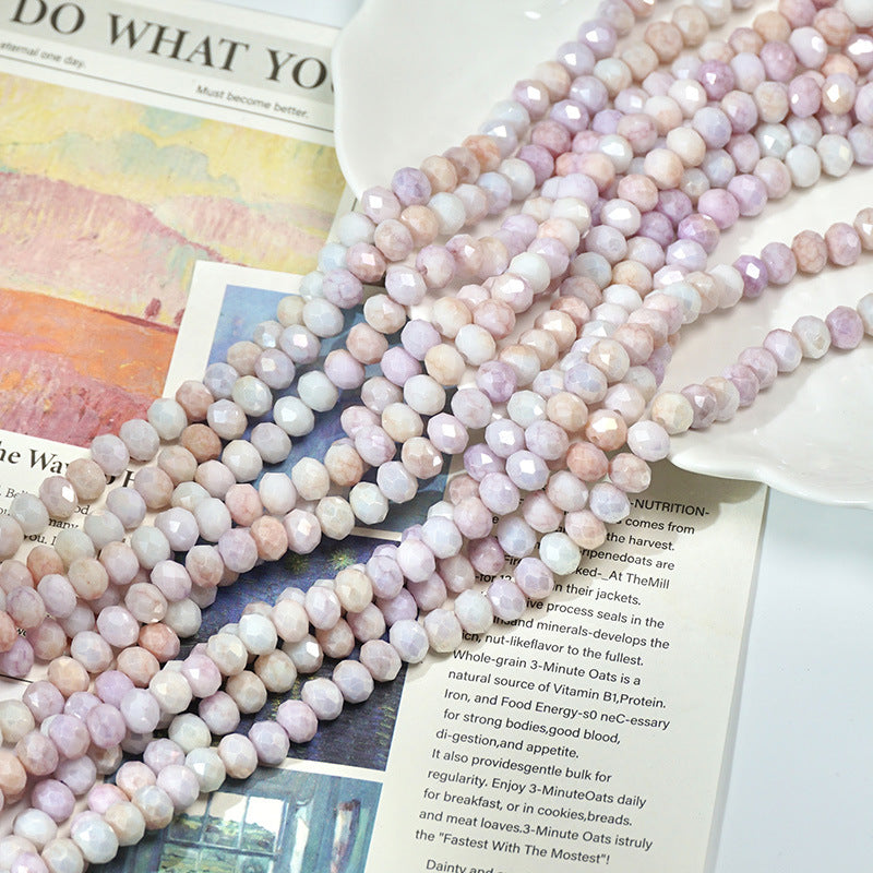 Long strands of pastel pink, lavender, and white faceted porcelain beads on a book