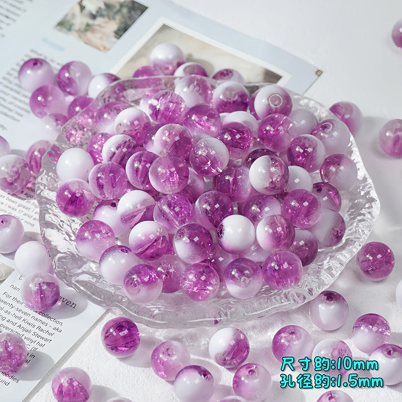 Purple and white gradient round beads with glitter, displayed in a clear glass dish on a white surface with printed papers.