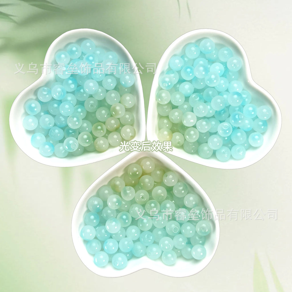 Three heart-shaped dishes of pale aqua and mint translucent beads on light green