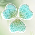 Three heart-shaped dishes of pale aqua and mint translucent beads on light green