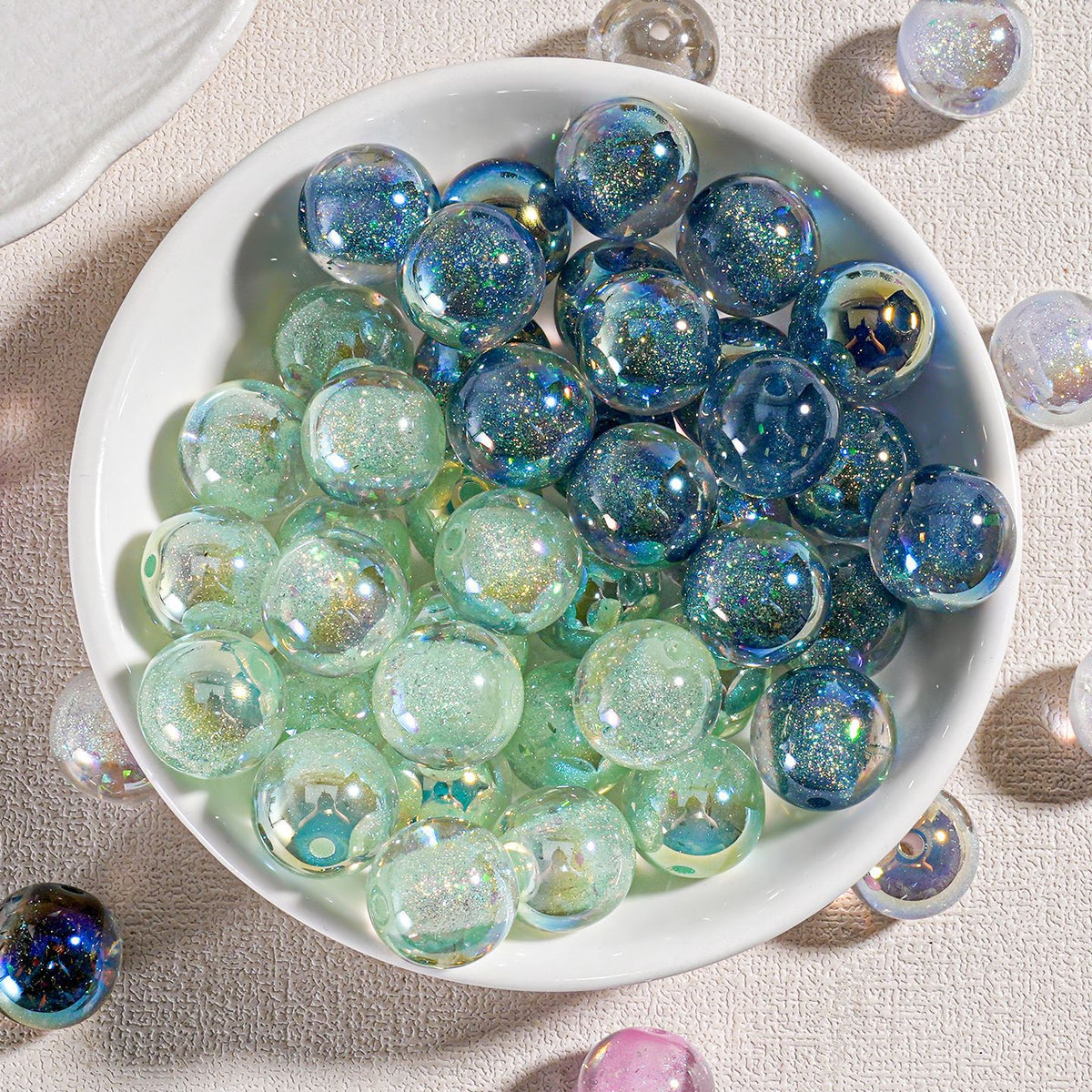 White bowl filled with round iridescent candy-core opal-effect resin beads in blue, green and purple