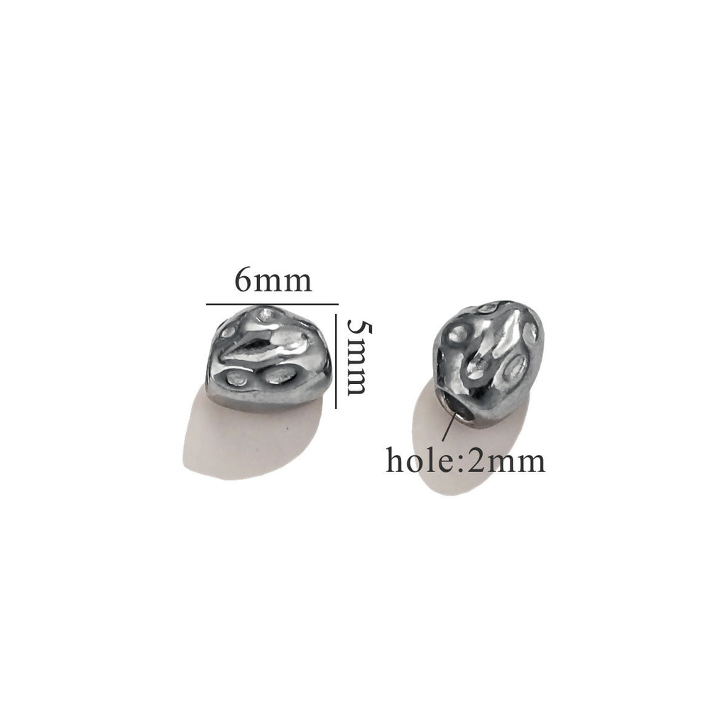 Two small black baroque connector bead pieces with matte finish on white background