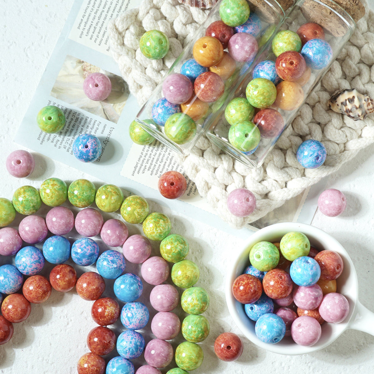 Multicolored marbled round glass beads in bottles, loose strands, and a white bowl