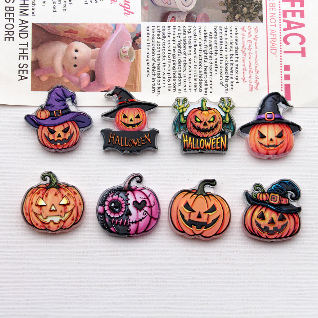 Eight Halloween-themed acrylic pumpkin charms with witch hats in two rows on a white textured surface