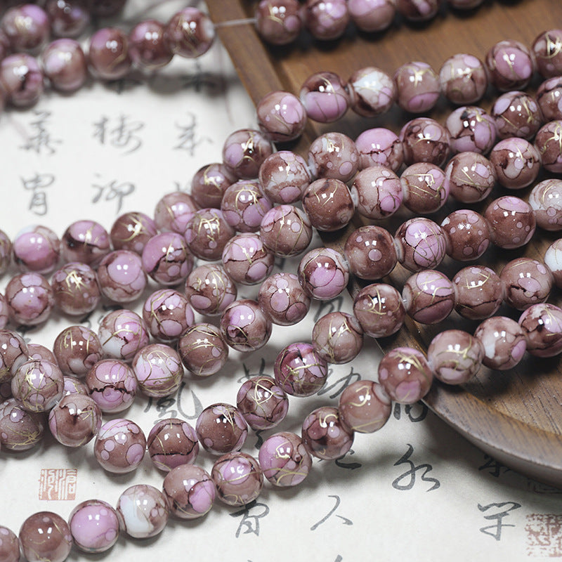 Close-up of pink-mauve marbled porcelain beads with brown accents on a light surface