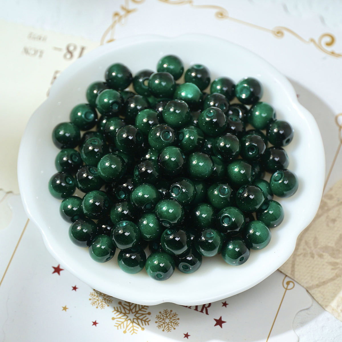 Glossy dark green round glass beads in a white scalloped bowl