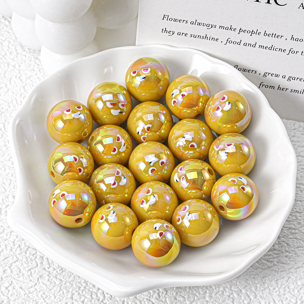 Shiny yellow iridescent resin beads with cartoon faces in white ceramic dish on textured surface with book page
