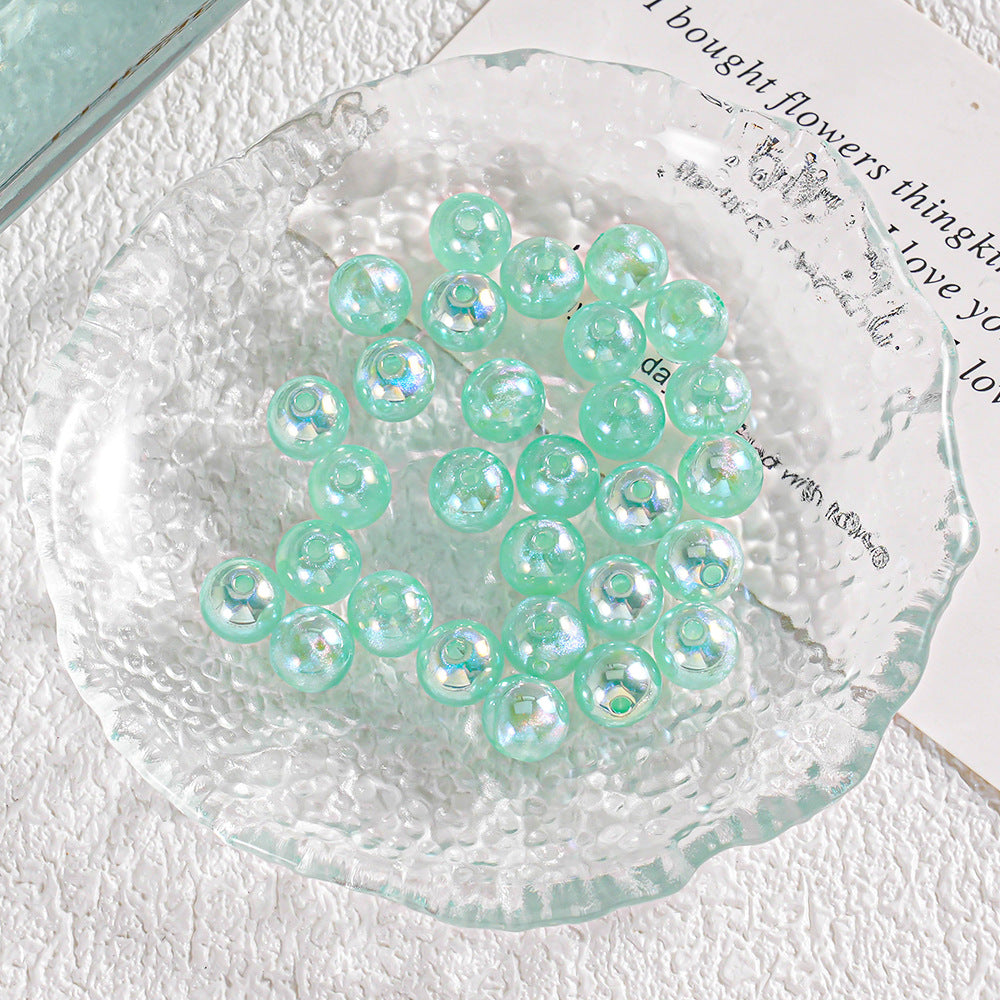 Round iridescent aqua beads with glittery finish on clear textured glass
