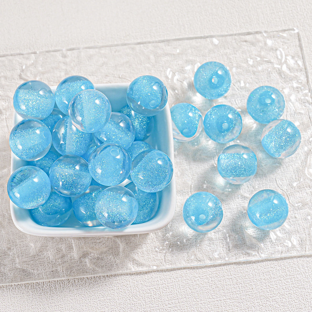 Light blue glittery round beads in a white dish and scattered on clear textured plate