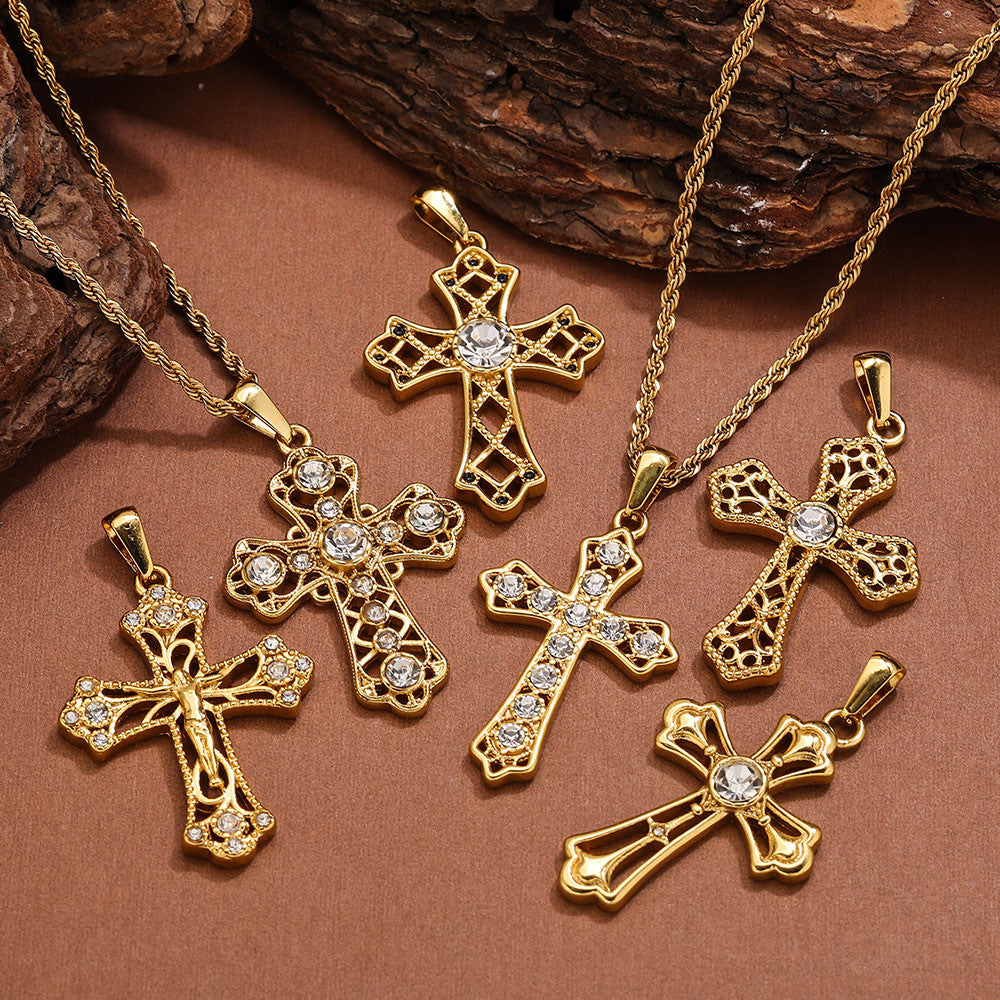 Six gold cross pendant necklaces with filigree designs and rhinestones on a brown surface with wood