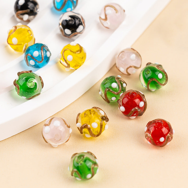 Colorful gold-sand swirl polka-dot glass beads on a beige surface