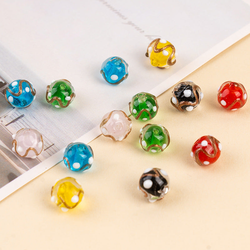 Colorful gold-sand swirl polka-dot glass beads on a beige surface