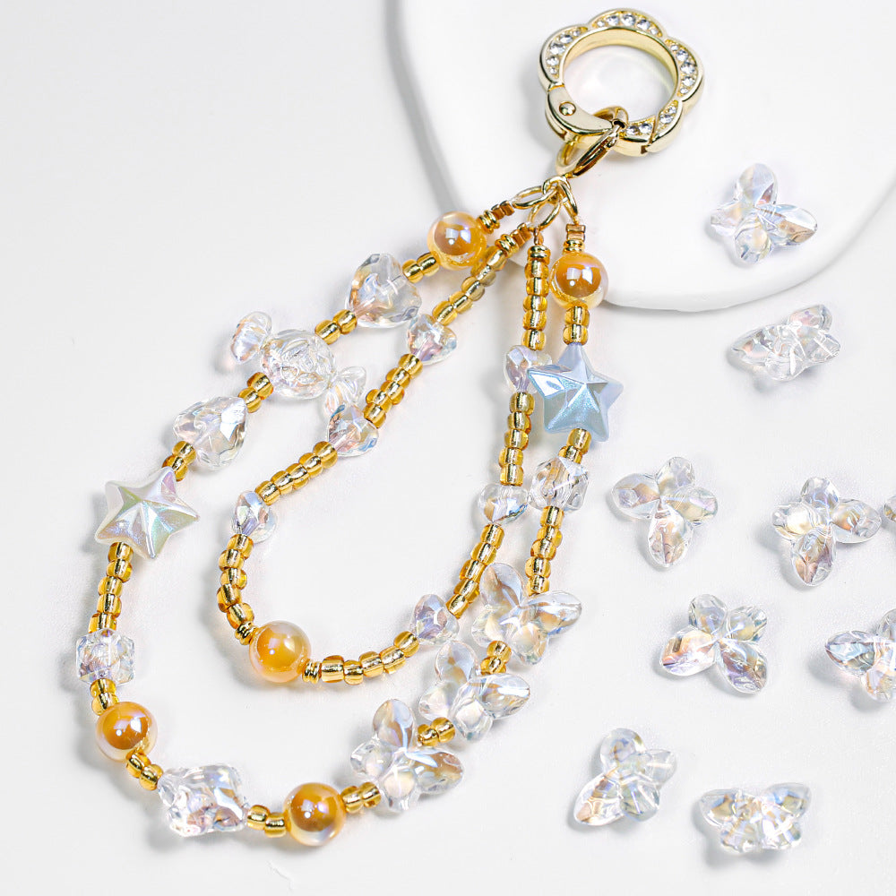 Gold-tone beaded phone strap with clear faceted butterfly beads, amber beads and star charms on white surface