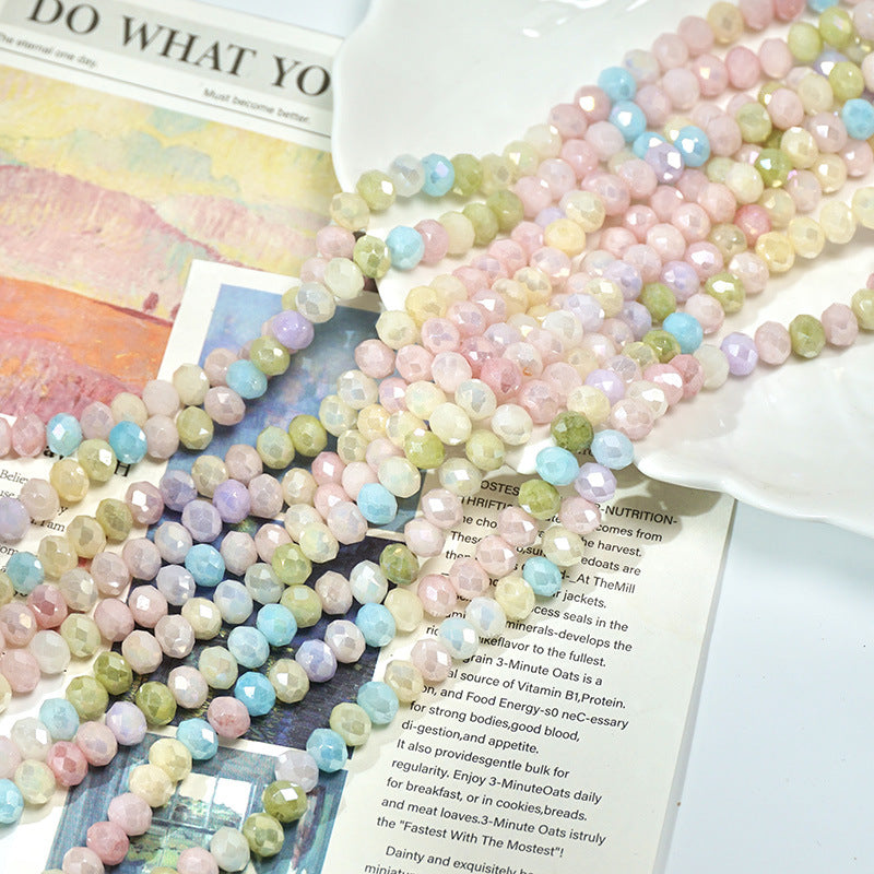 Pastel rainbow faceted porcelain round beads on printed papers and a white dish