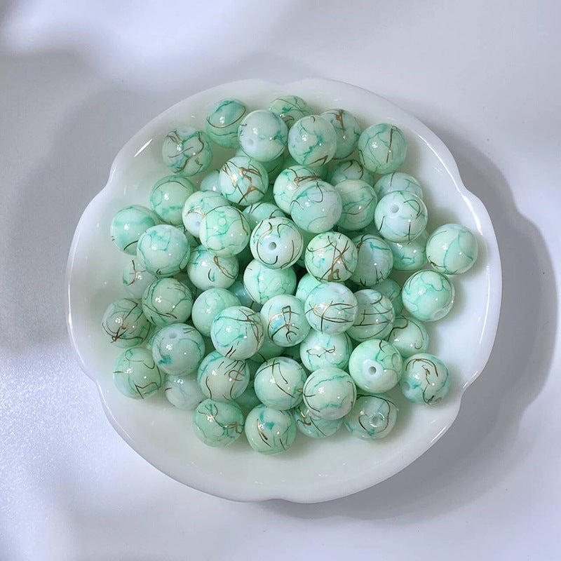 White bowl of marbled mint-green glass beads with gold-silk veining