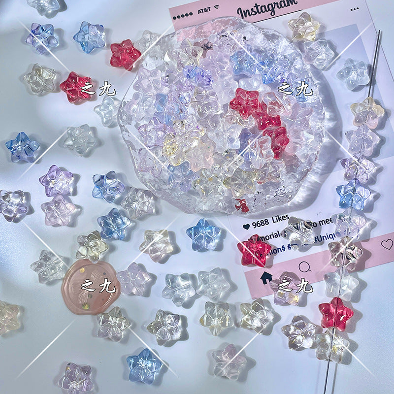 Translucent star-shaped glass beads in clear, pink, red, blue, and purple on a white surface