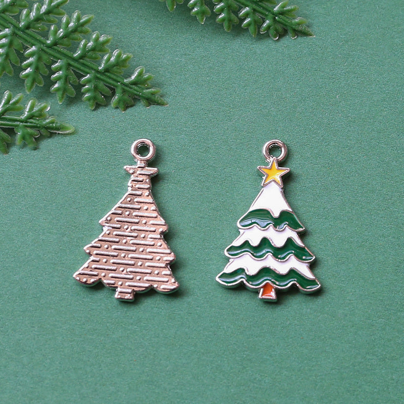 Two Christmas tree-shaped jewelry charms on textured green background