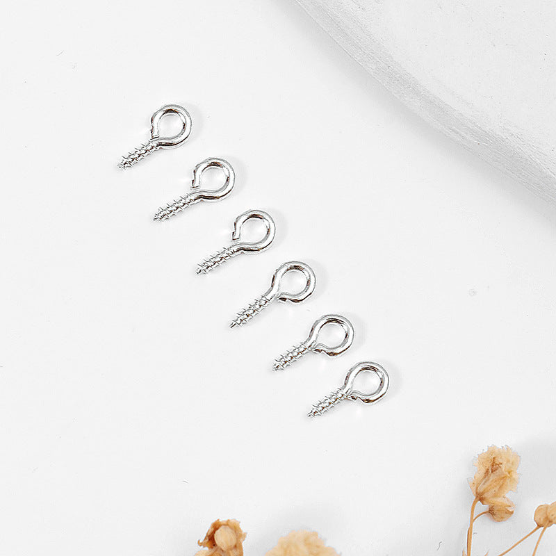 Five small silver screw eye pins with threaded shafts arranged diagonally on white
