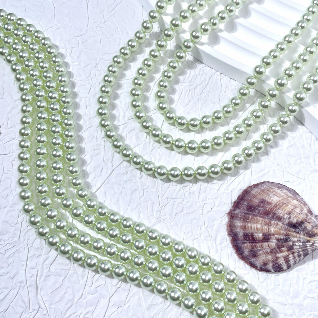 Multiple strands of pale greenish-white glass pearl beads with seashell