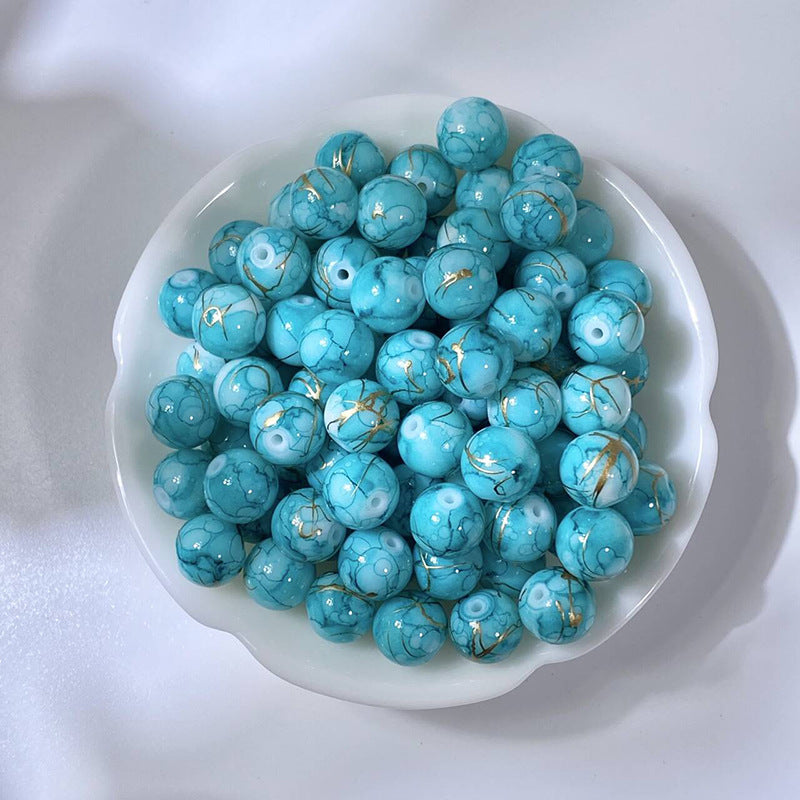 White bowl of marbled turquoise glass beads with gold-silk veining