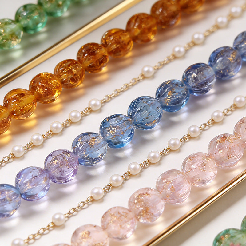 Strands of gold-sand lantern glass beads on a white surface with gold trim