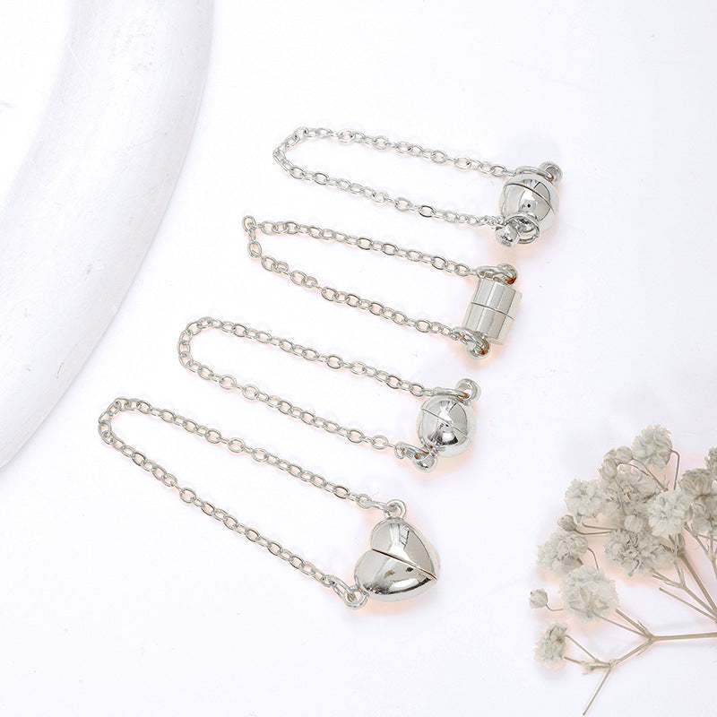 Four silver magnetic clasps with safety chains in ball, cylinder, and heart shapes on white with dried flowers