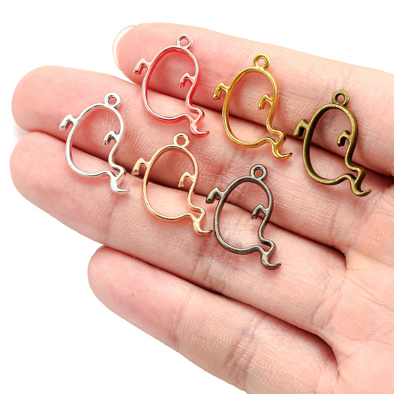 Five ghost-shaped charms in silver, rose gold, yellow gold, bronze and dark metal on an open hand