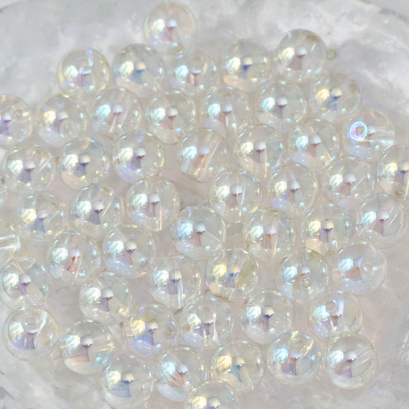A pile of round, iridescent clear beads with a subtle rainbow sheen, resting on a white textured surface.