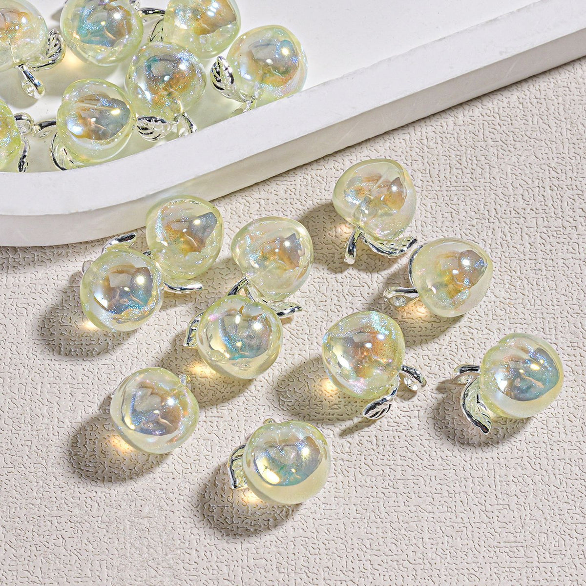 Several iridescent heart-shaped mini peach beads with silver metal settings scattered on a textured surface