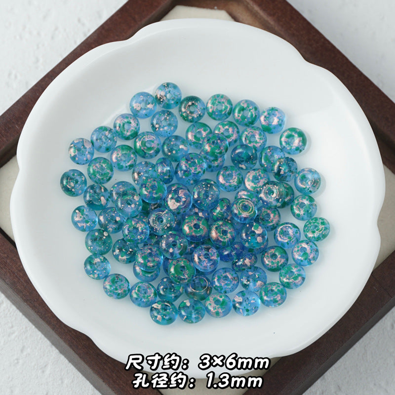 Blue and green marbled Picasso glass abacus beads with white glitter in a white scalloped dish.
