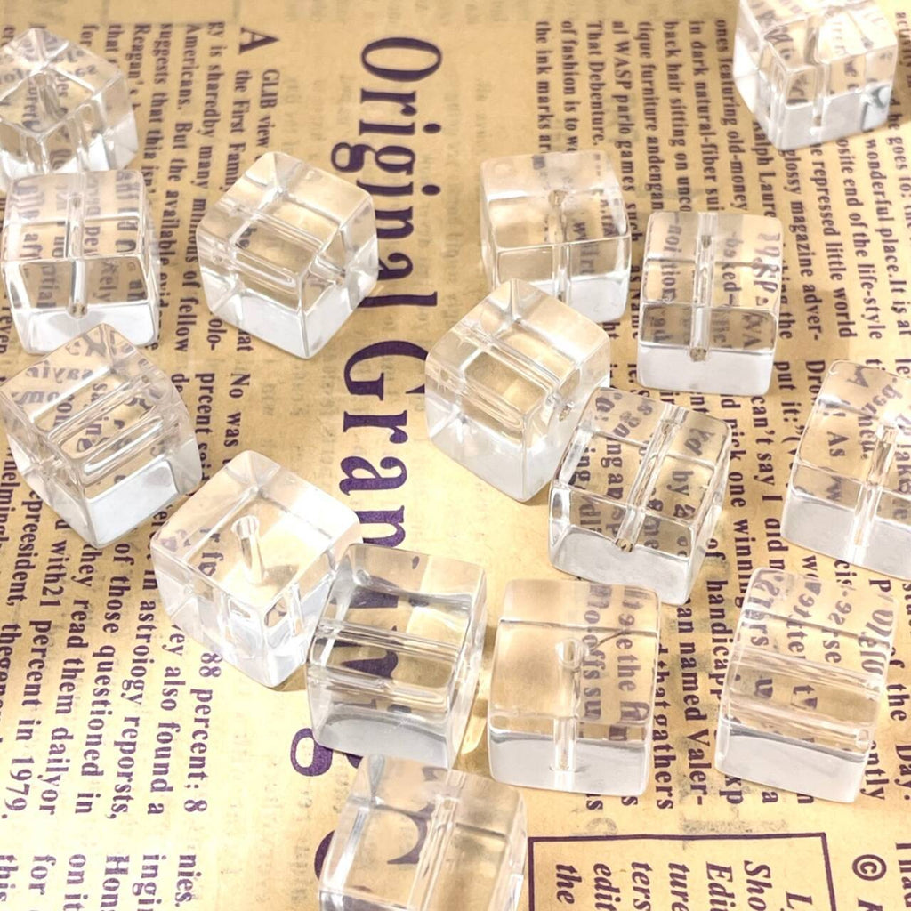 Clear cube-shaped glass beads scattered on a vintage newspaper background
