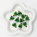 Six small Christmas tree-shaped beaded ornaments in green, red, and clear glass on white