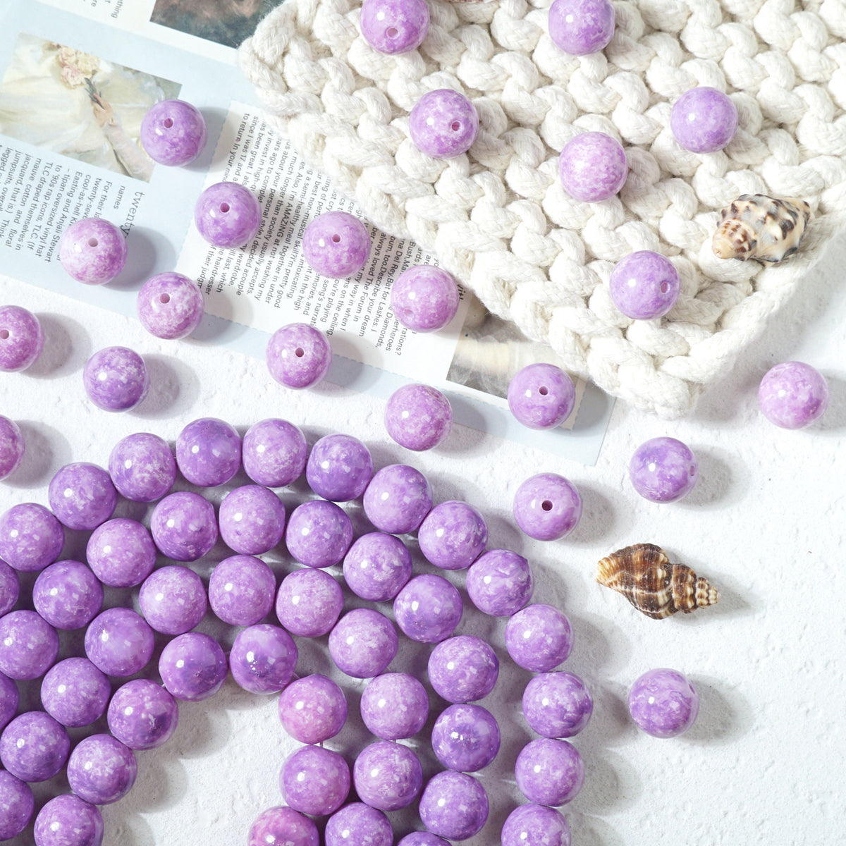 Purple marbled round glass beads with drilled holes on a white textured surface