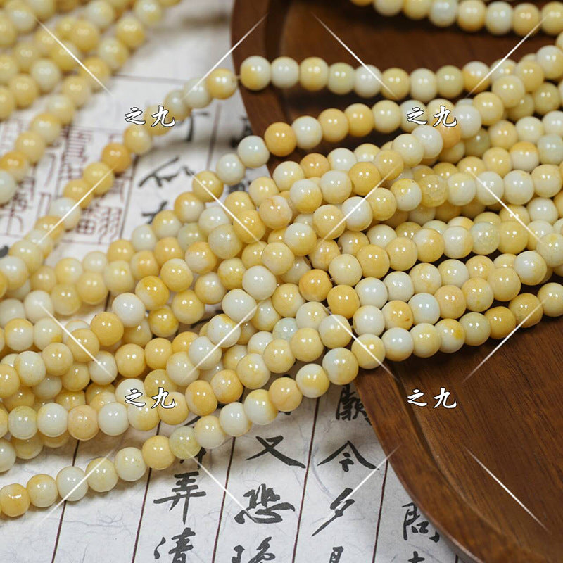 Multiple strands of round polished porcelain beads in cream, pale yellow, off-white