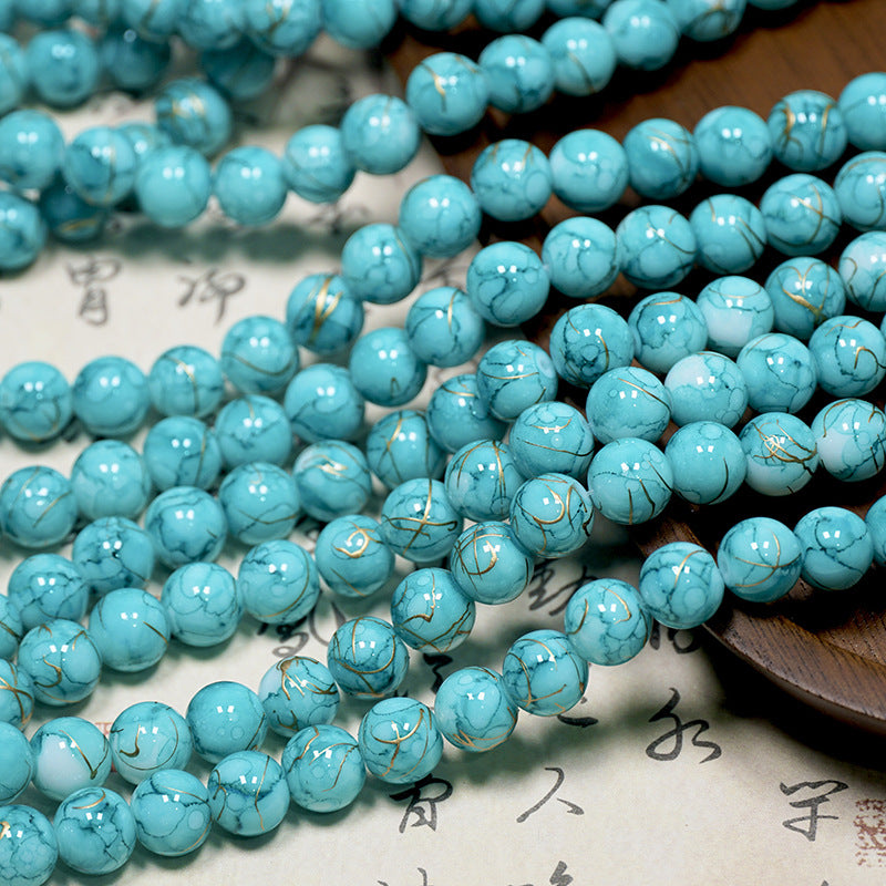 Turquoise blue porcelain bead strands with white and gray veining on paper
