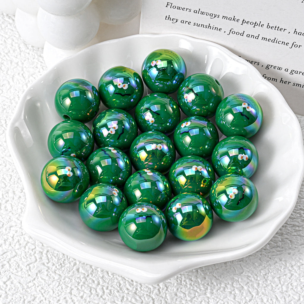 Glossy green iridescent resin beads with cartoon faces in white ceramic dish on textured white surface
