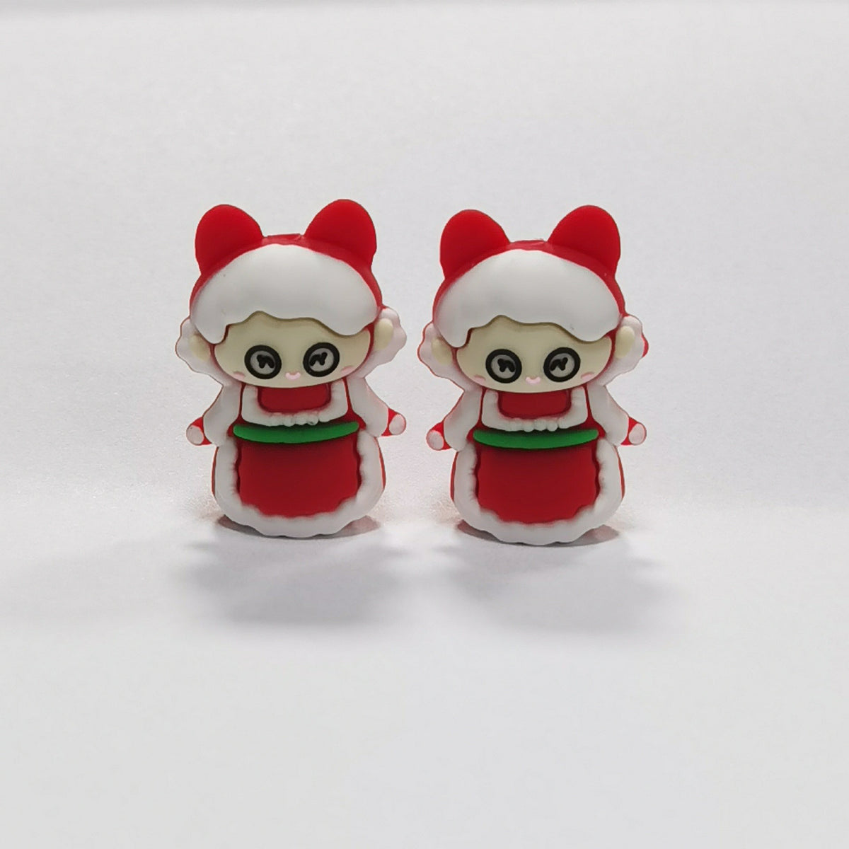 Two cartoon children silicone focal beads in red and white outfits with green accents and bear-ear hoods