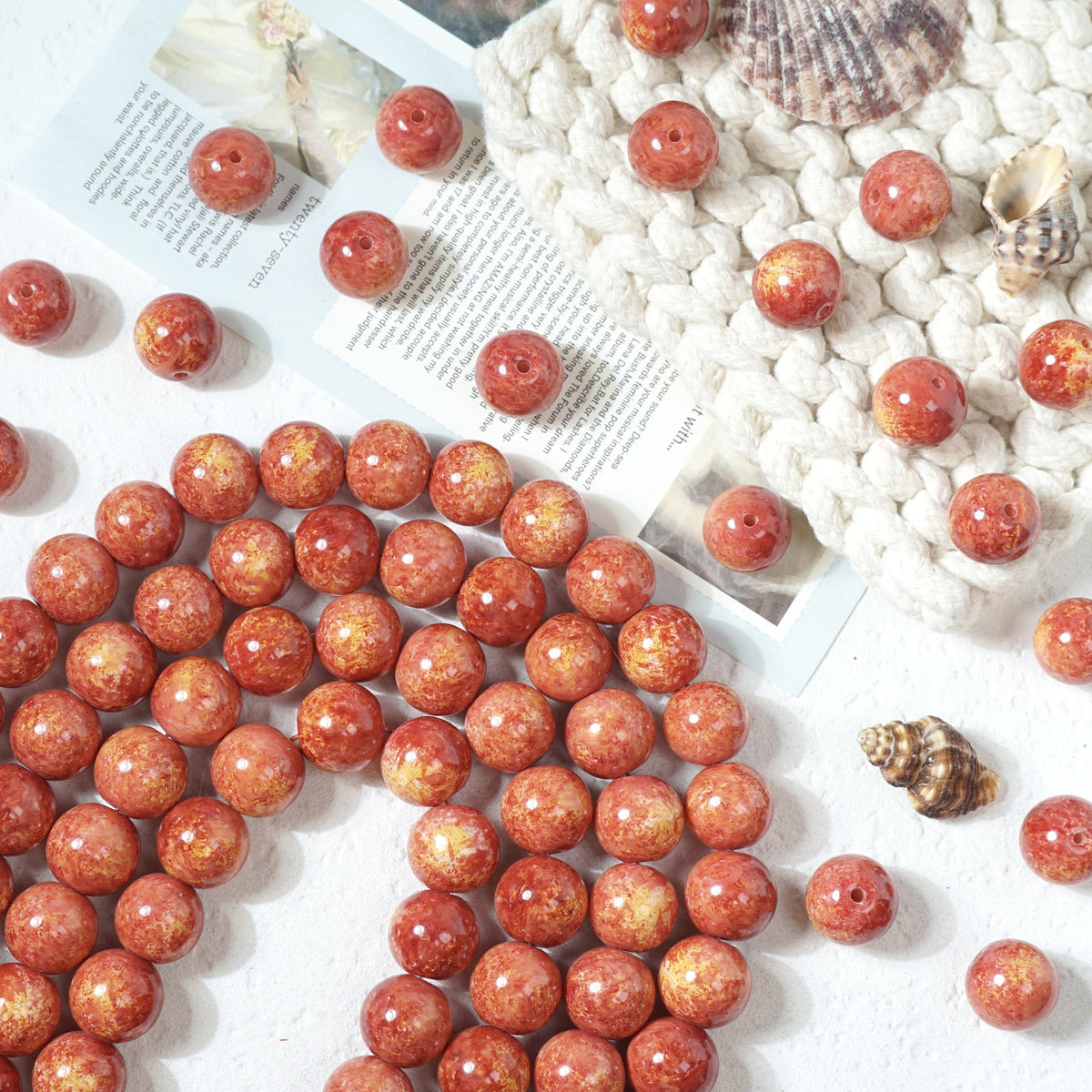 Orange-red marbled round glass beads with yellow and white inclusions on white