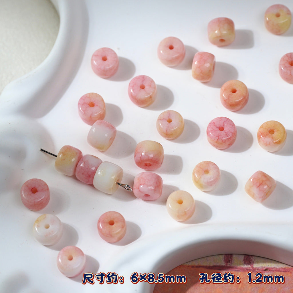 Pink and peach marbled round porcelain beads on white tray, one strand threaded
